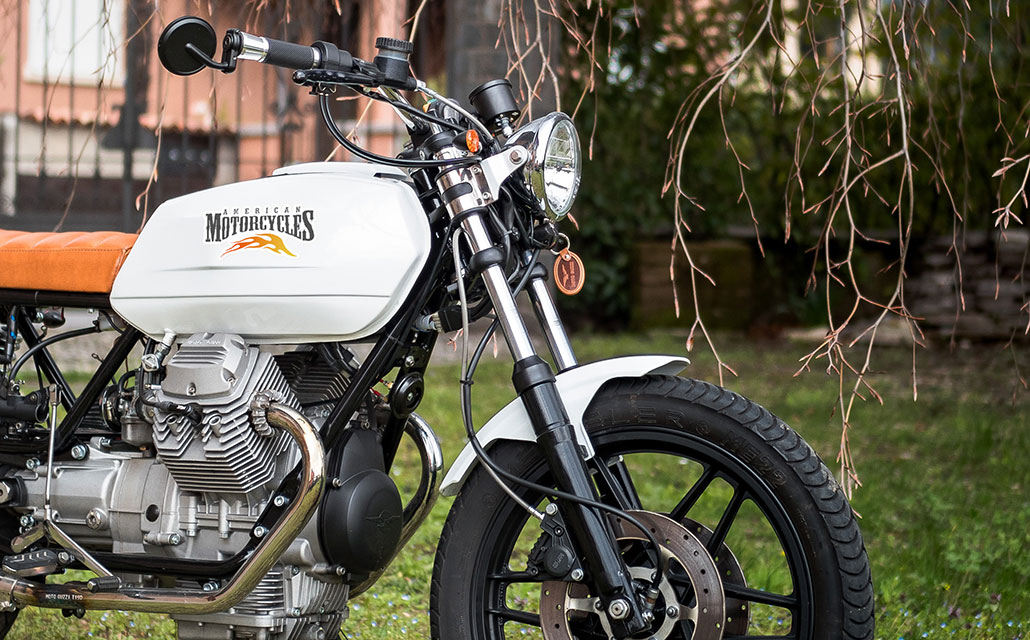 A parked motorcycle with unique made stickers on the gas tank.