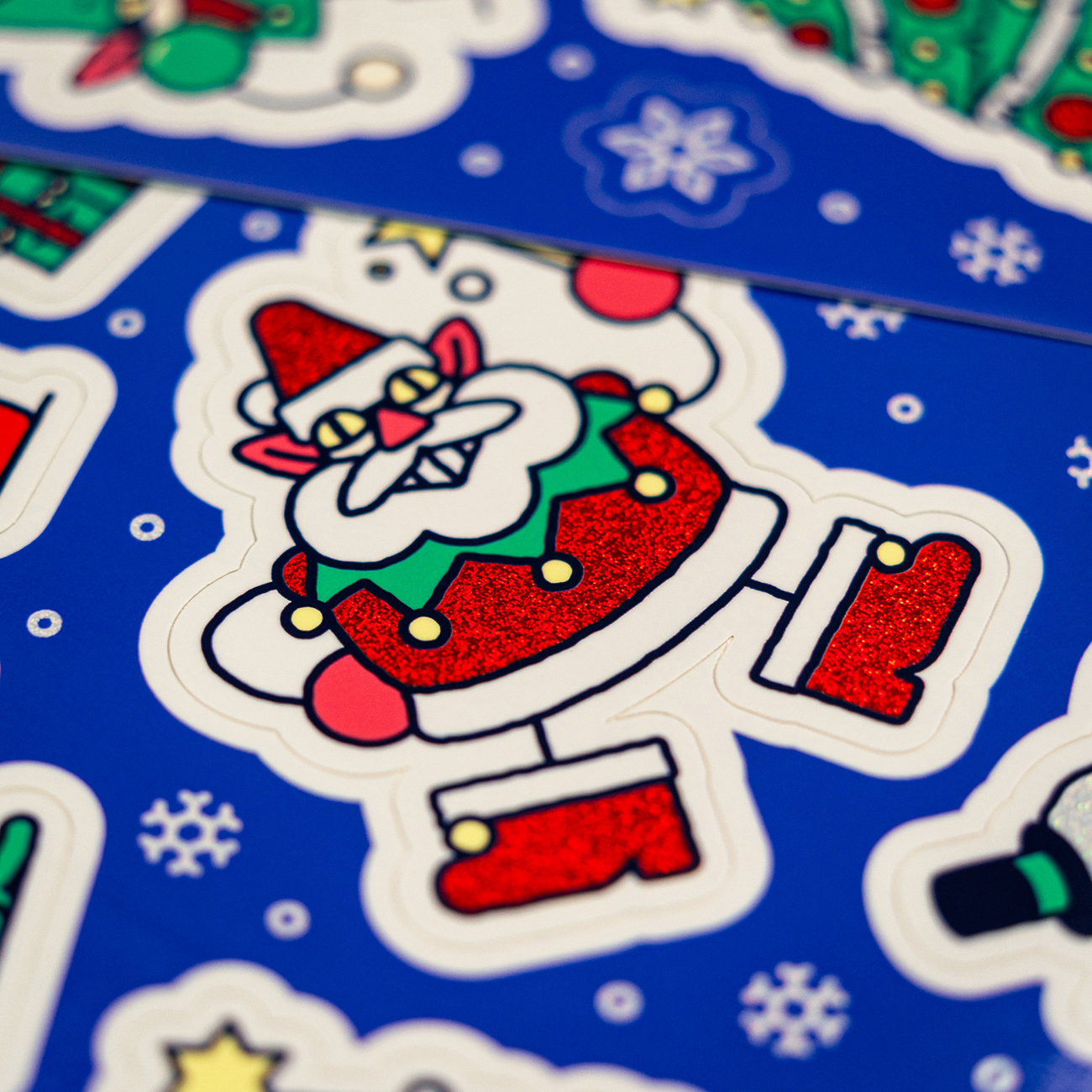 Santa christmas creeper printed on a blue sticker sheet on Pixie Dust, surrounded by other sheets.
