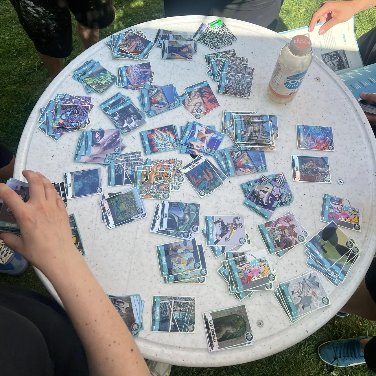Festival visitors filling blue sticker albums with collectible street art sticker cards spread across a round table