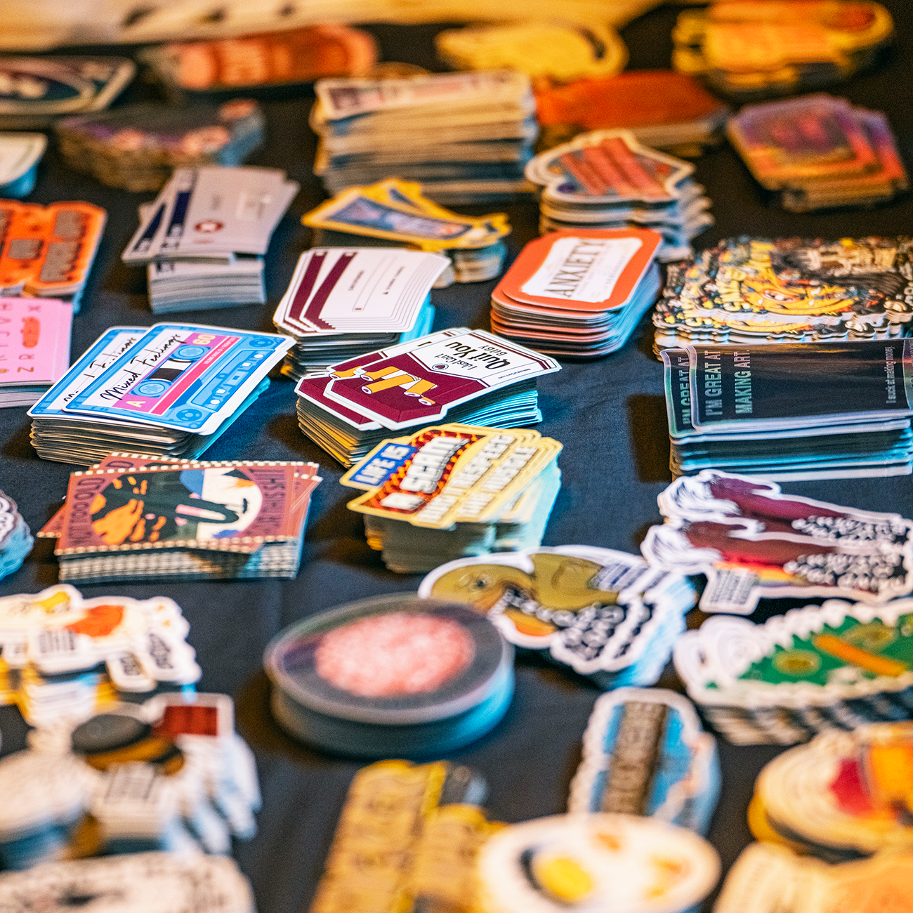 Die-cut stickers printed in various materials and sizes sitting on a dark table