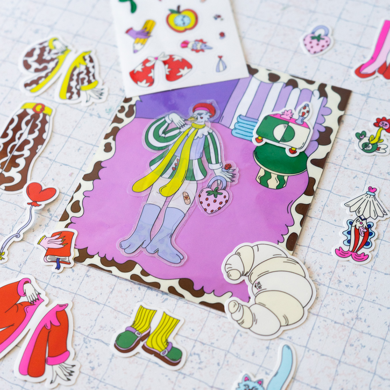Transparent stickers laying on a sheet, with different characters and figures against a light background