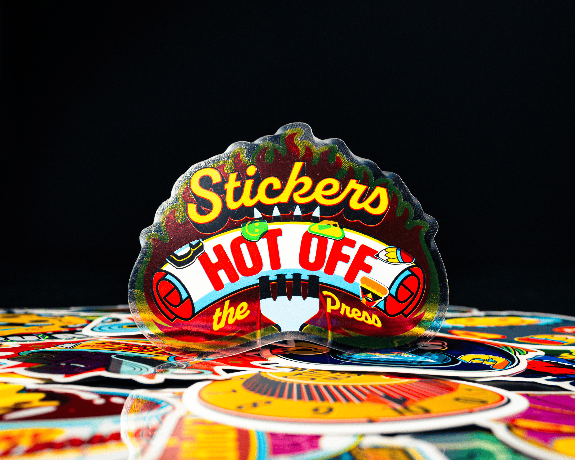 A colorful sticker that says "Stickers hot off the press"