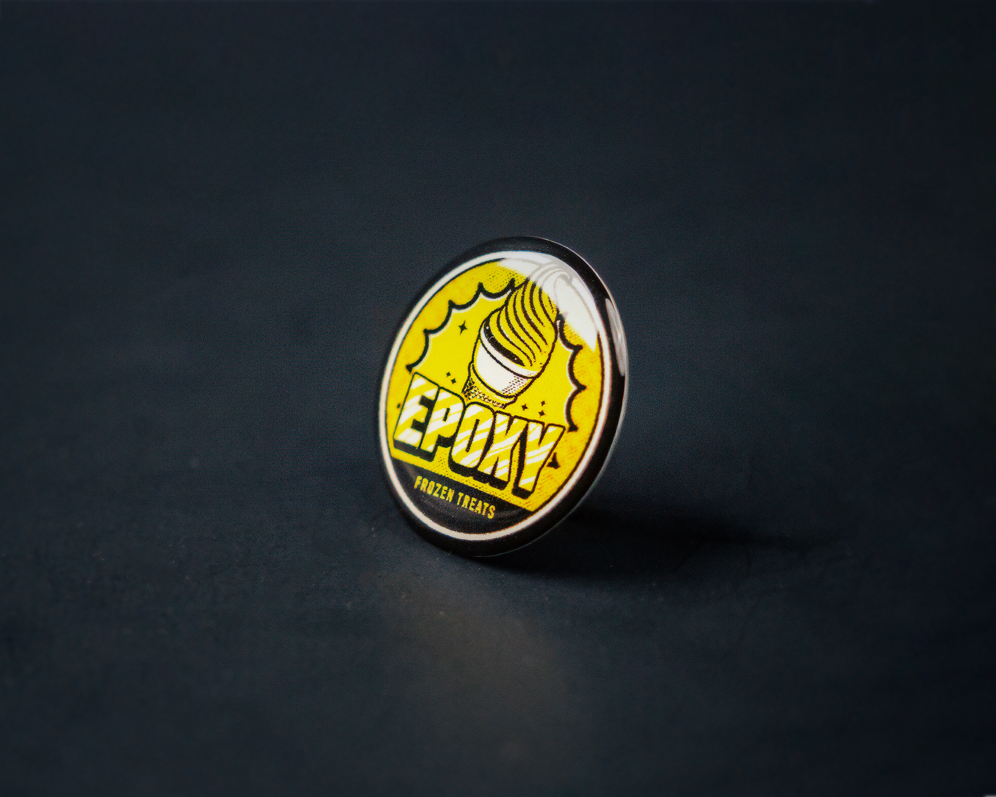 A round epoxy sticker with a yellow background, featuring a white ice cream cone and the text "Epoxy Frozen Treats" in bold letters.