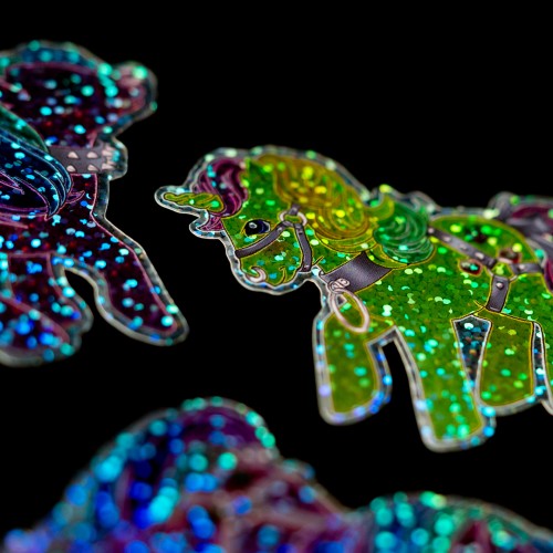 A close up of a colorful glitter sticker of a unicorn on a black background