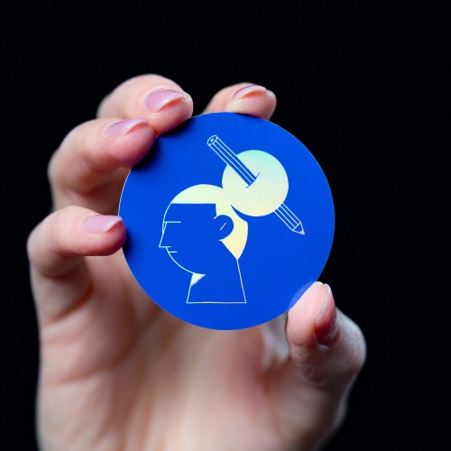 A blue holographic sticker with a picture of a woman with pen in the hair