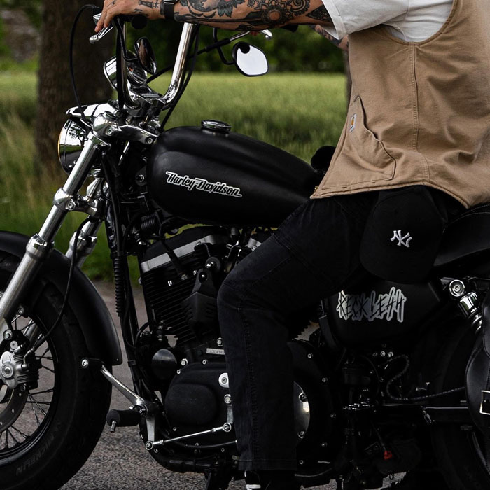 A man riding a motorcycle, and custom stickers on the bike.