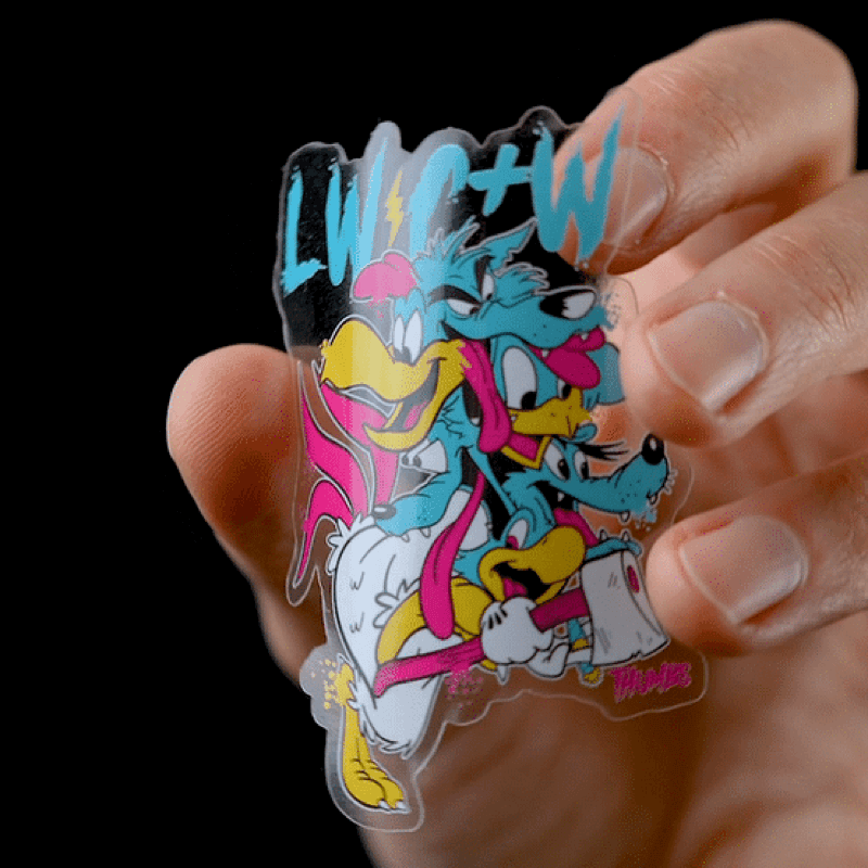 A hand holding a die cut transparent sticker with a cartoon character with an axe on it.